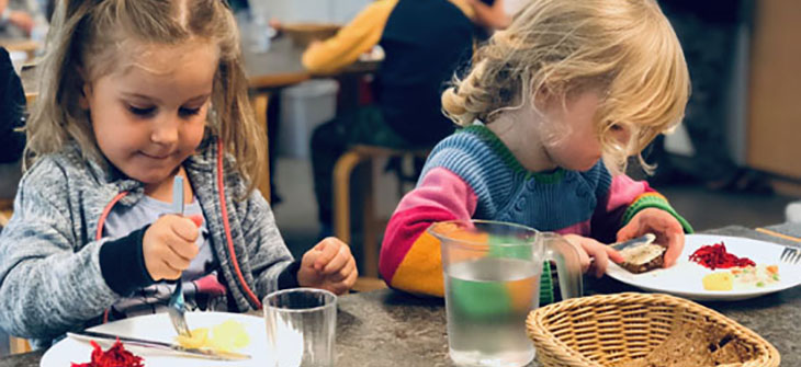 Billede af to børn som spiser frokost på stuen i Børnehaven Regnbuen